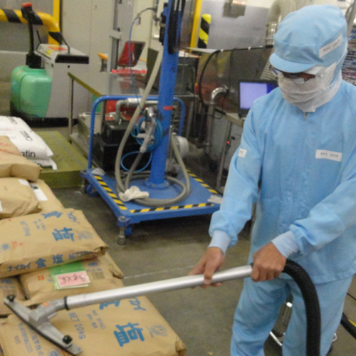 原料の袋の周りについているホコリなどを除去し、異物が工場に入り込むのを防いでいる様子